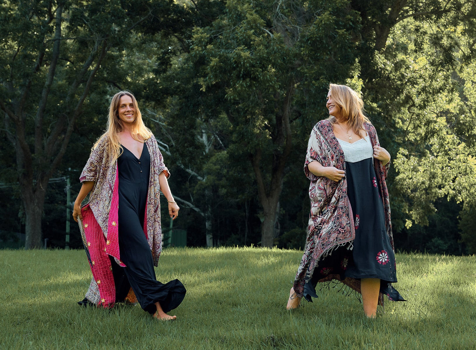 Two women walking outdoors in a park with trees in the background