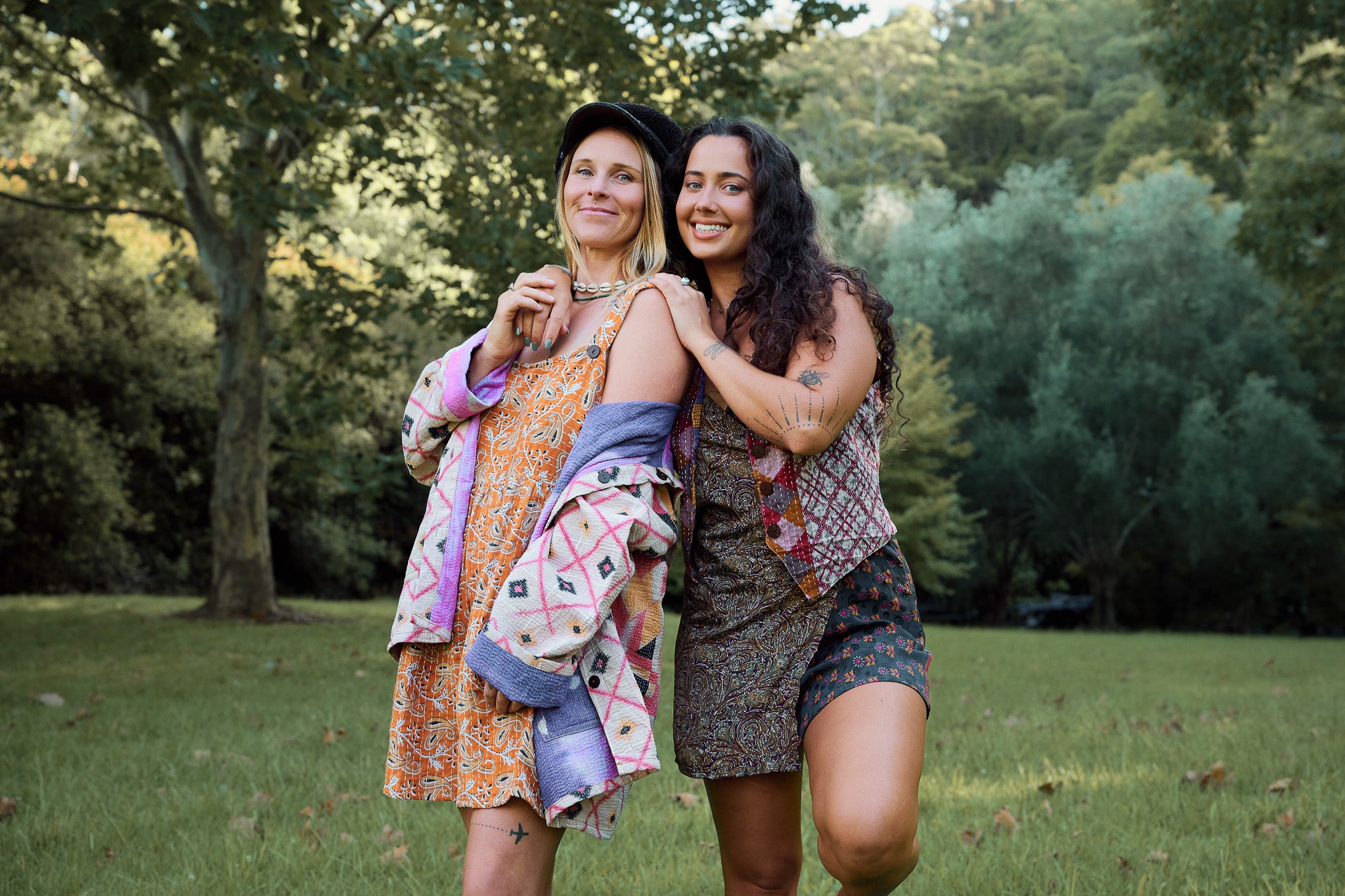Two women standing in a park with trees in the background