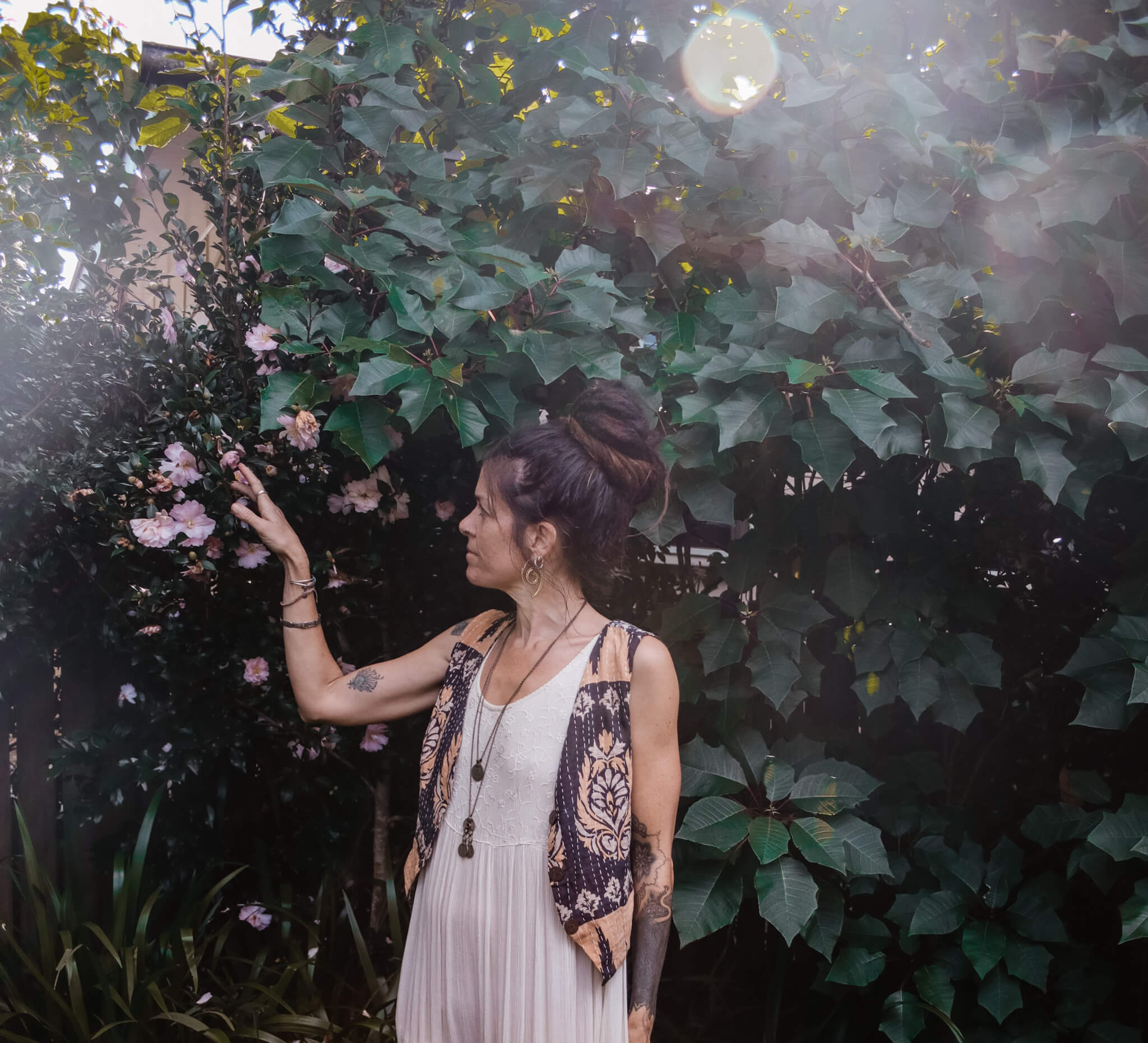 Woman in a white dress standing among green foliage and flowers