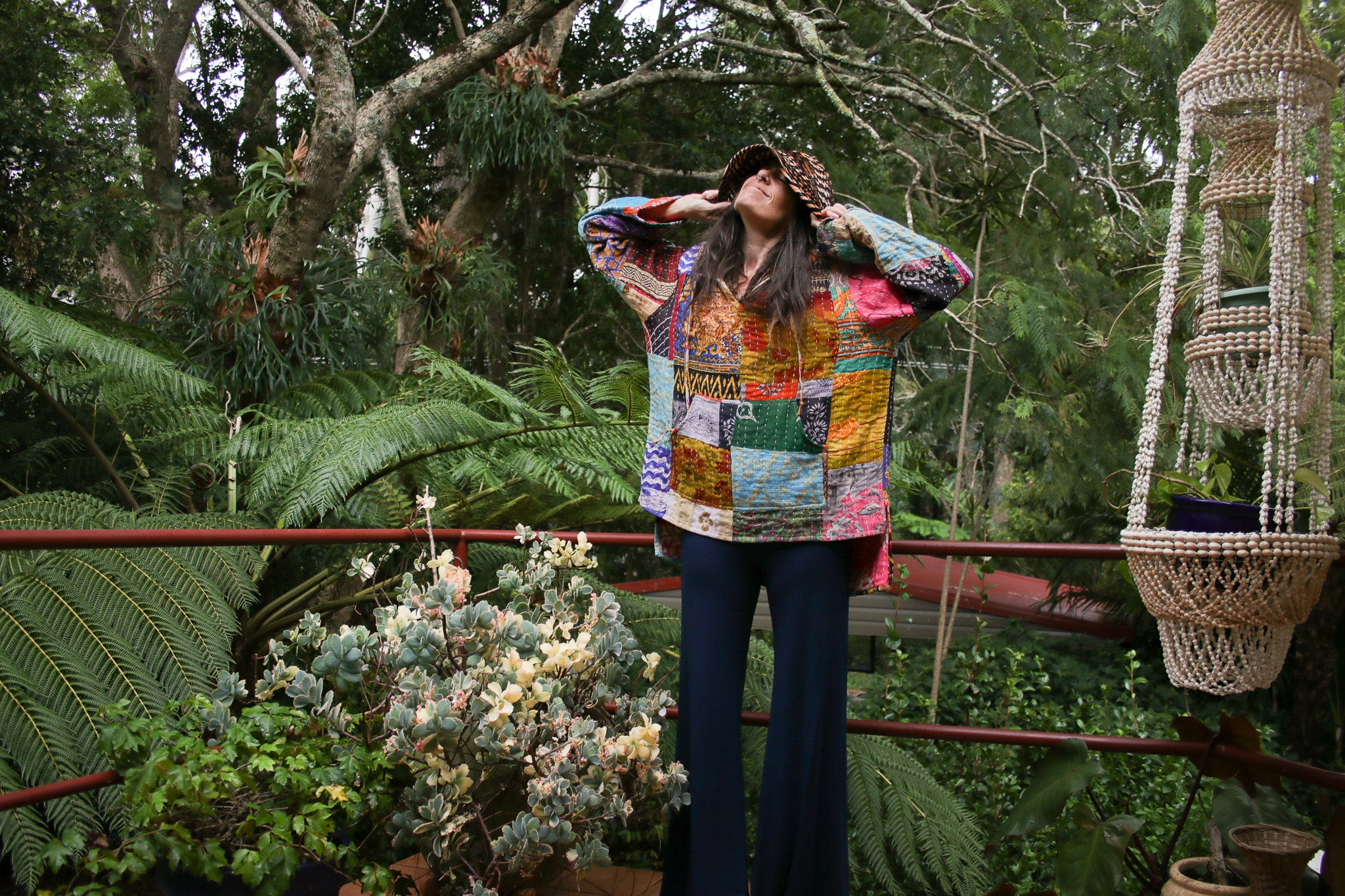 Person wearing a colorful patchwork jacket in a garden setting