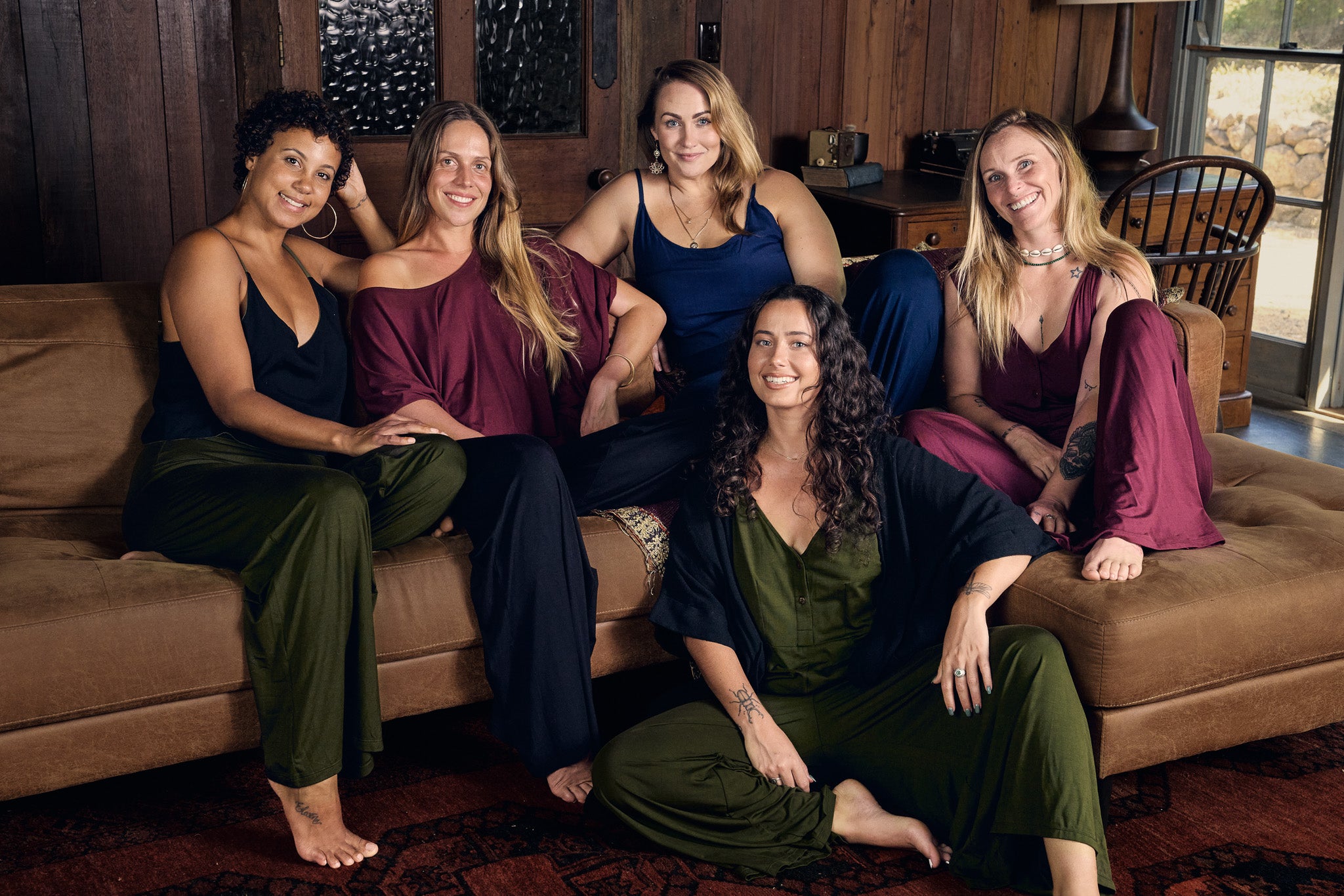 Five women sitting on a couch in a living room setting