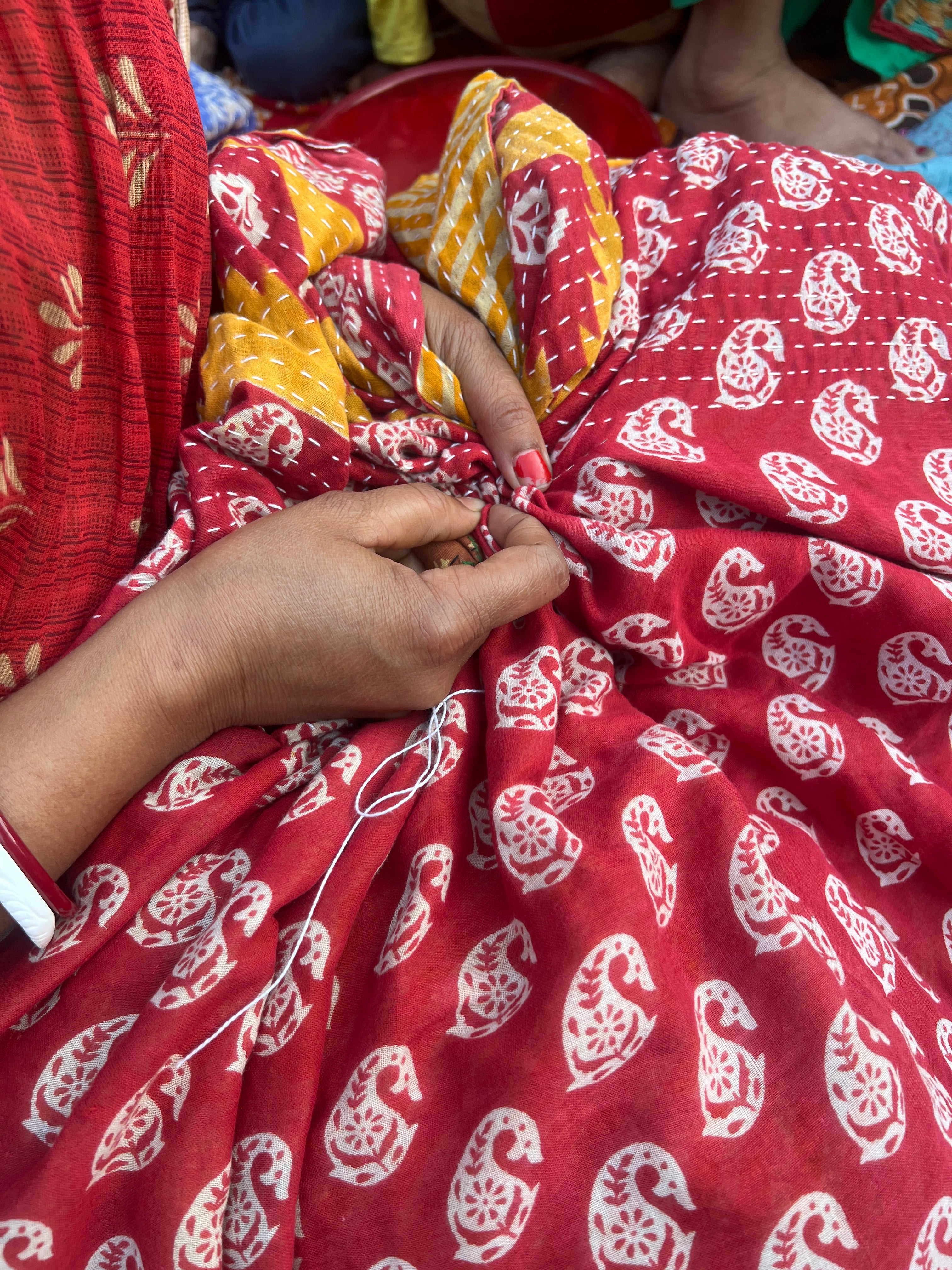 Red fabric with white patterns held by a person's hands