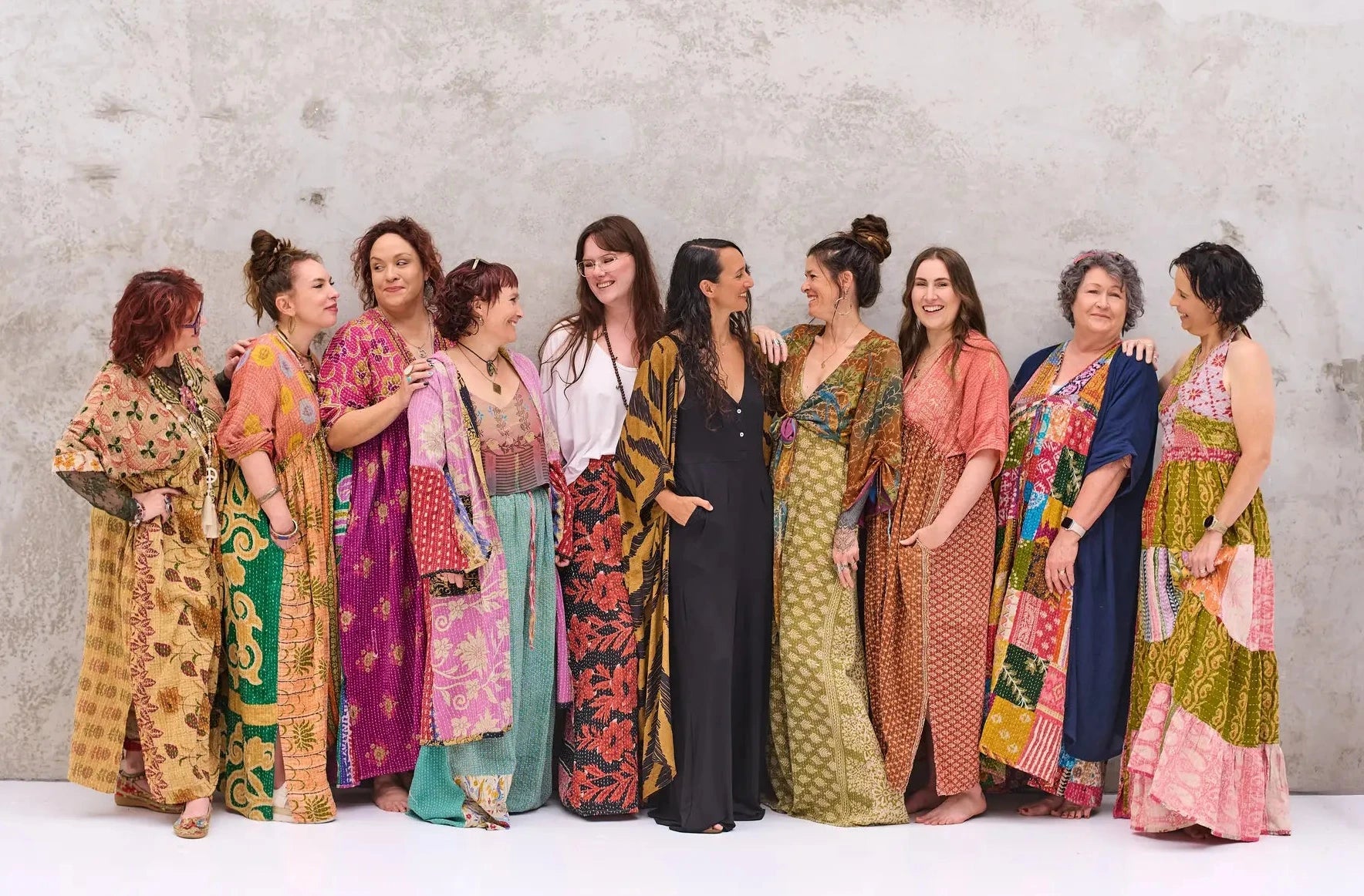 Group of women wearing colorful patterned dresses against a plain background