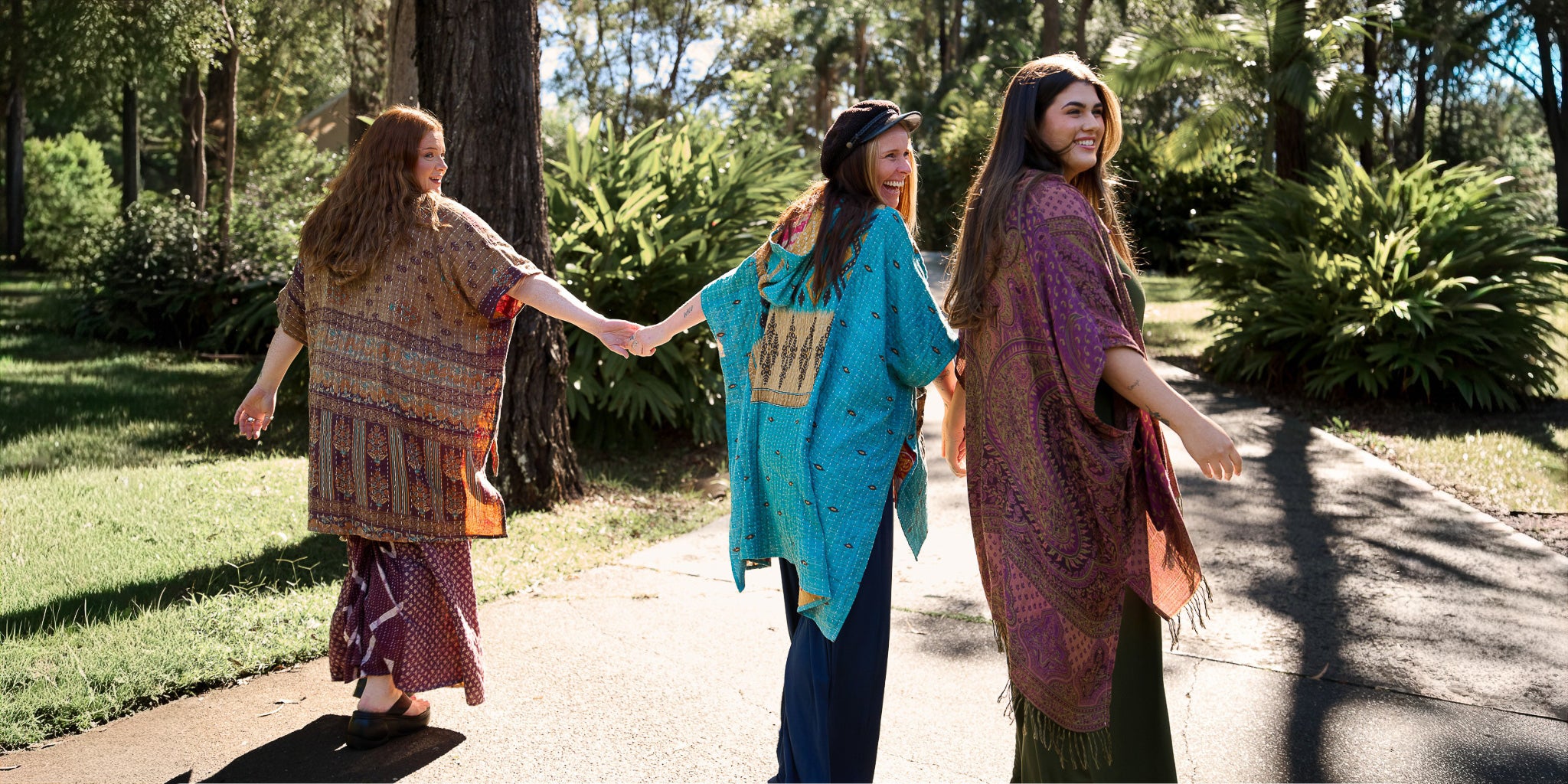 Three women laughing and walking up a path in colourful coats