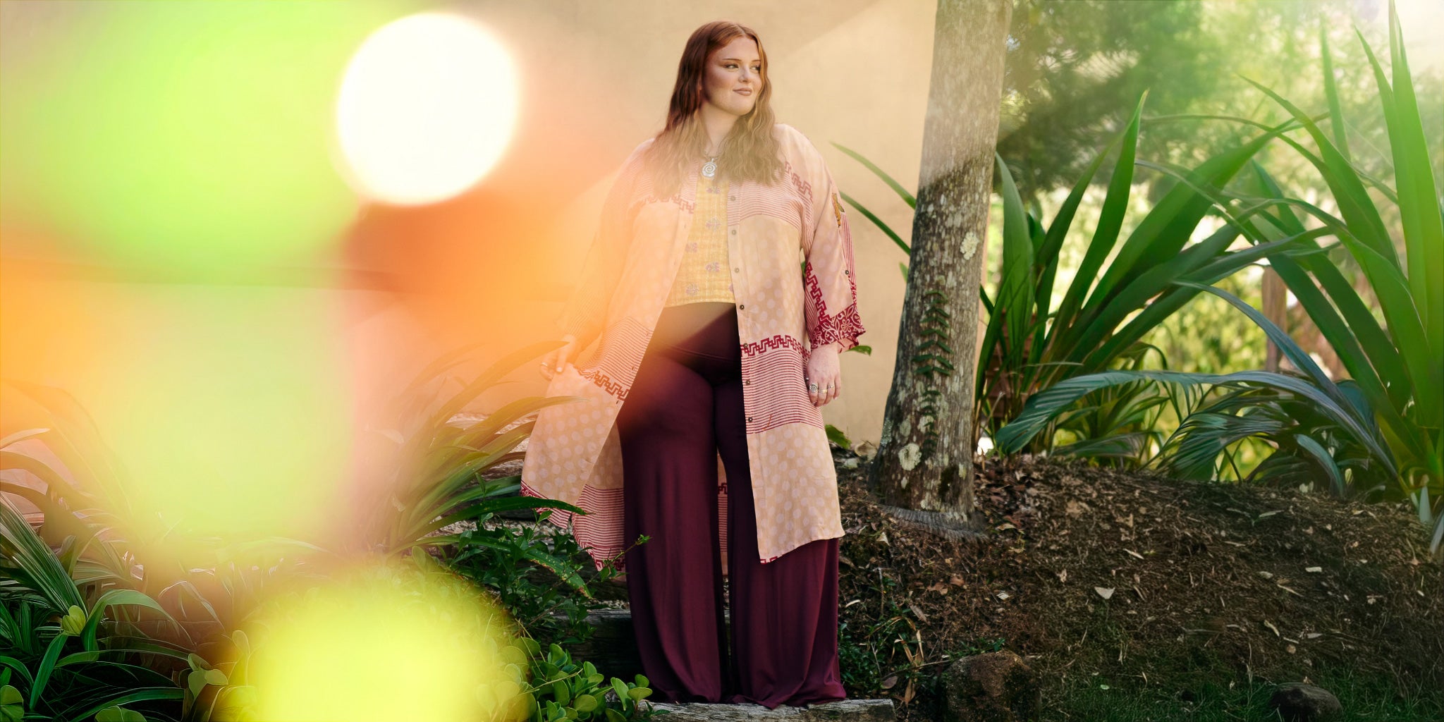 Woman in a floral dress standing in a garden with blurred lights in the foreground