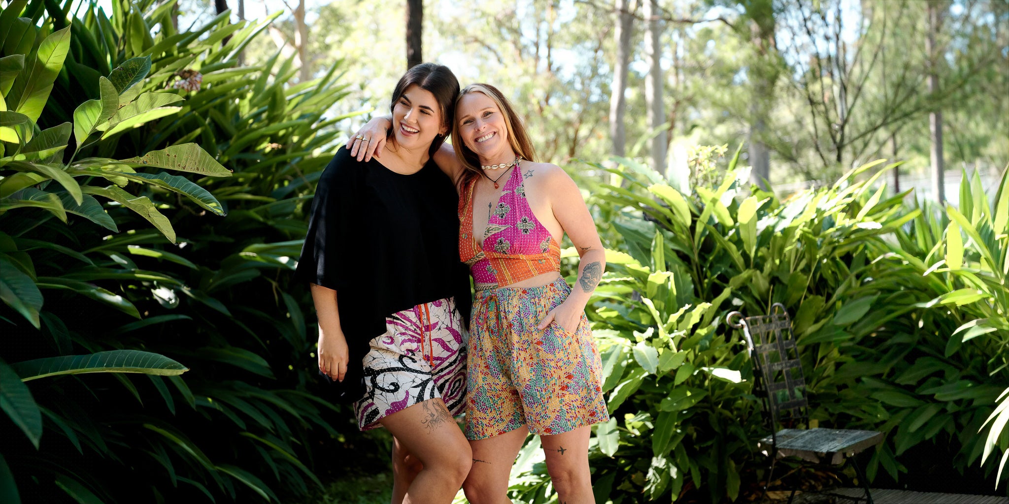 Two women standing in a garden with lush greenery
