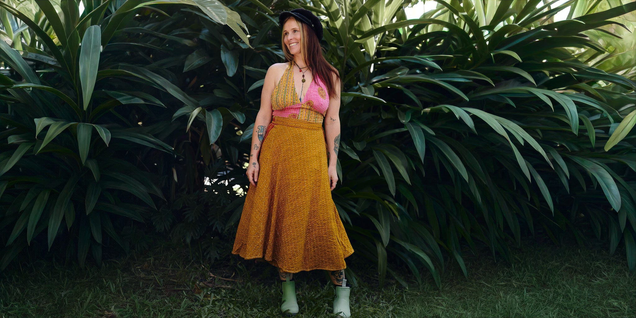Woman in a yellow dress standing among large green plants