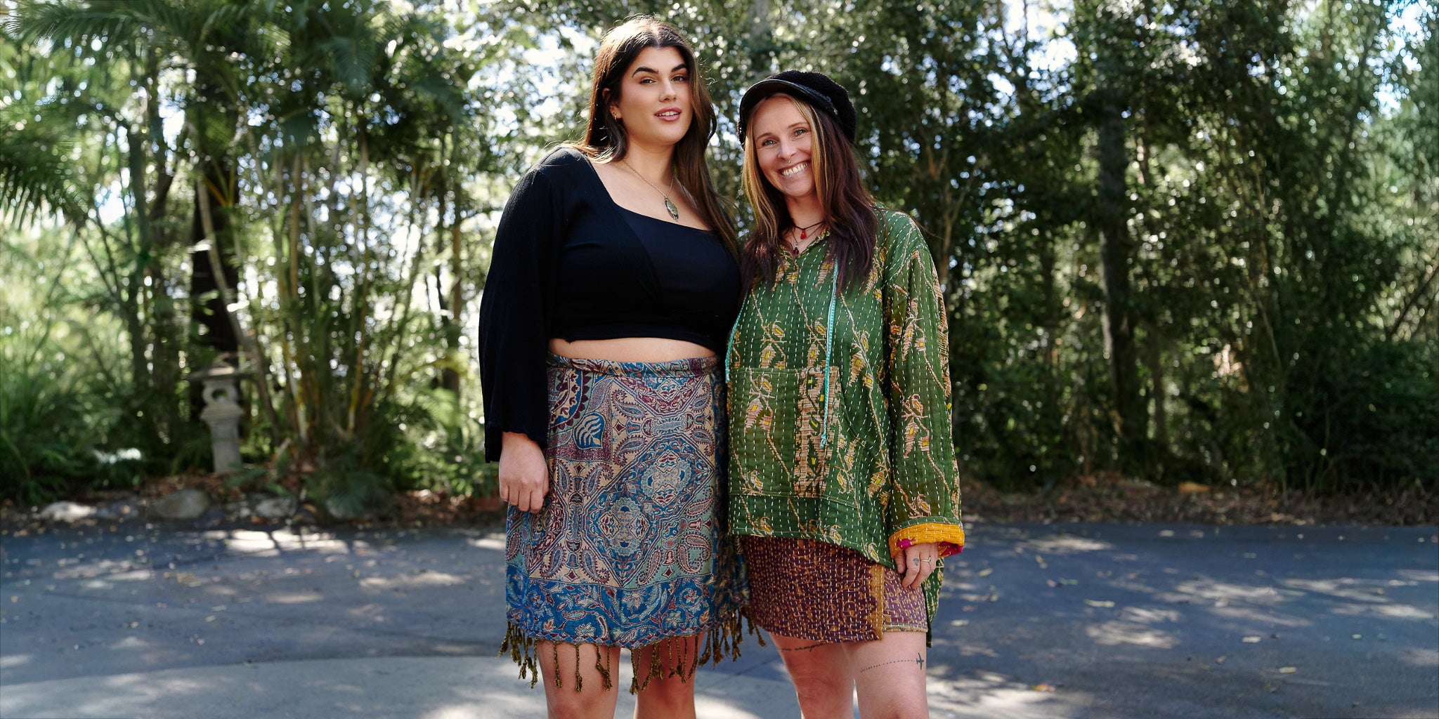 Two women standing outdoors with trees in the background