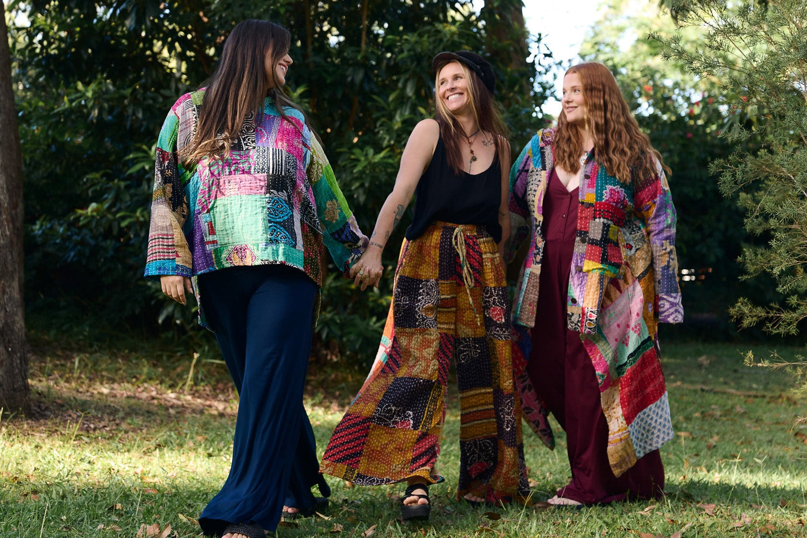 Three women walking outdoors in colorful, patterned clothing.