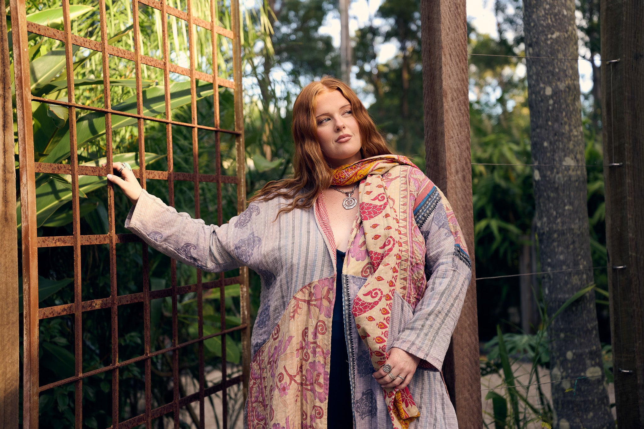 Woman wearing a colorful patterned shawl in a garden setting