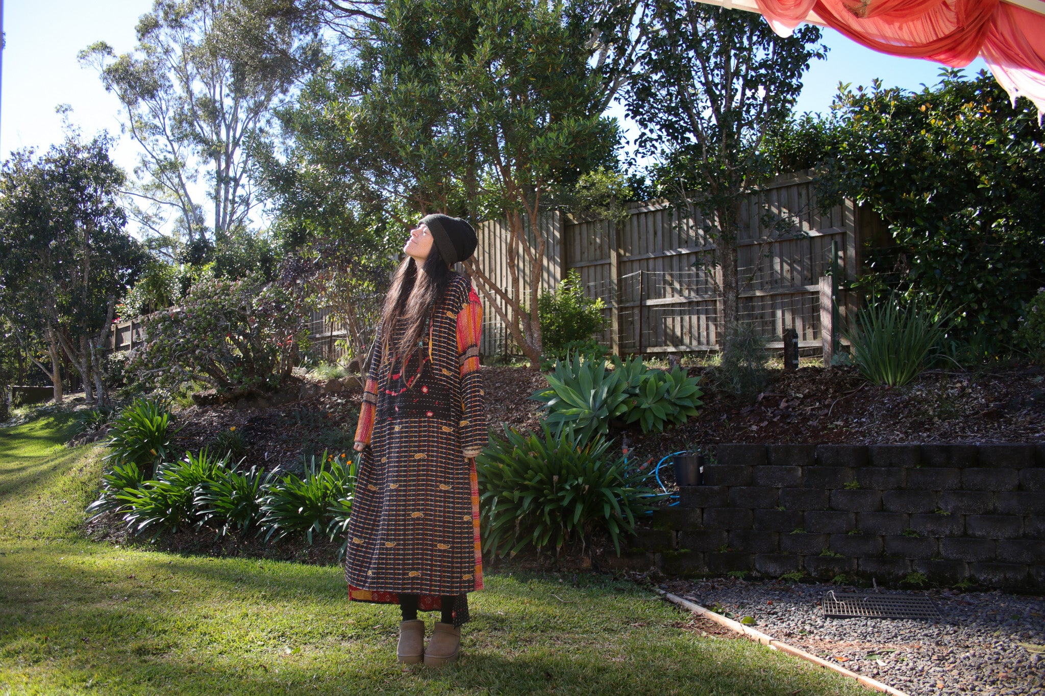 Person standing in a garden with trees and plants around